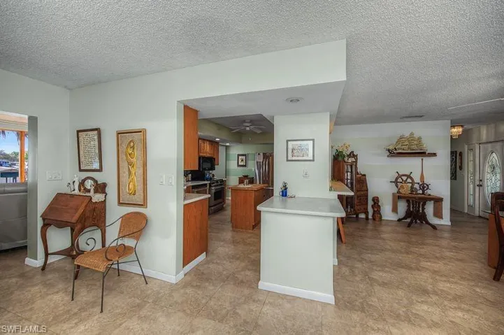 Kitchen featuring Corian countertops, a textured ceiling, wood  cabinets, a ceiling fan, and stainless steel appliances