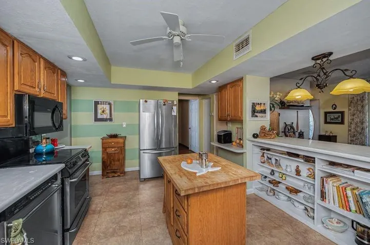 Kitchen featuring stainless steel appliances, Crian Couinters, butcher block top on island, wood cabinets, and a ceiling fan