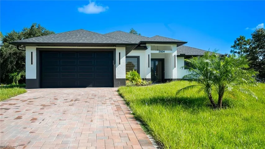 Modern exterior with white stucco finish, dark asphalt shingle roof, and paver driveway