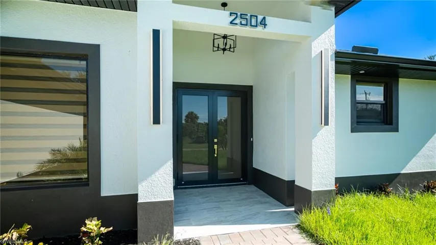 Stucco exterior with a two-tone finish, dual front entry doors, and a covered entryway