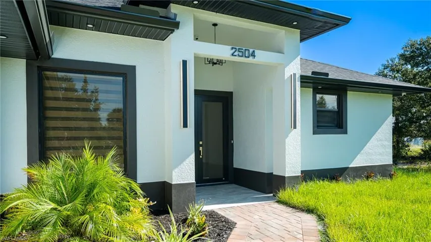 Modern stucco exterior with black trim accents and a paver walkway