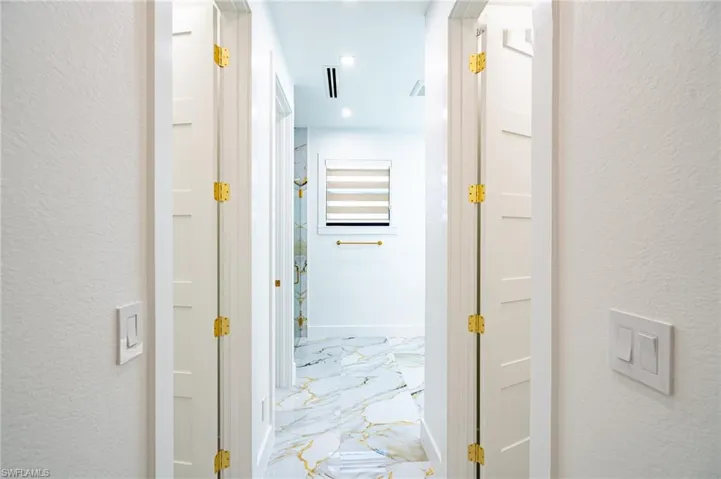 White paneled doors with brass hardware, recessed lighting, and patterned flooring