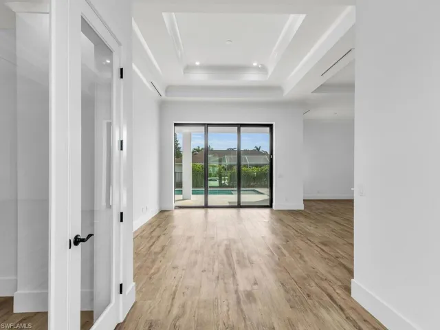 Spare room featuring a tray ceiling, baseboards, wood finished floors, and recessed lighting