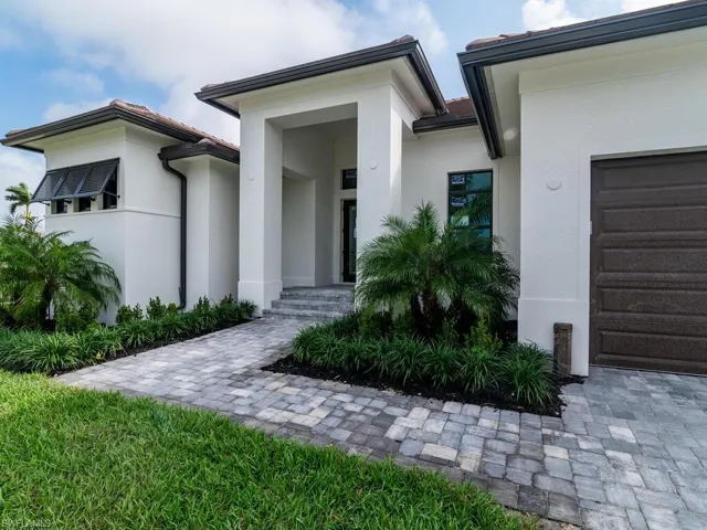 Doorway to property with stucco siding, an attached garage, and a tiled roof