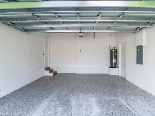 Garage with water heater, a garage door opener, and electric panel
