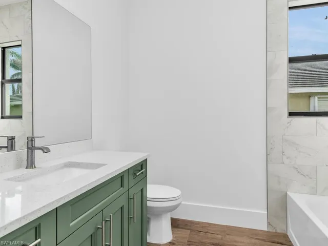 Full bathroom with vanity, a bathing tub, toilet, baseboards, and wood finished floors