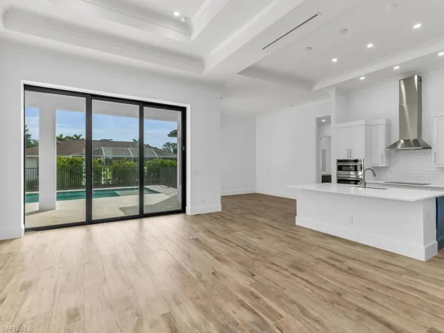Unfurnished living room featuring light wood finished floors, baseboards, ornamental molding, recessed lighting, and a sink