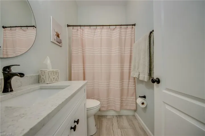 Hall bath featuring vanity, shower / tub combo with curtain,