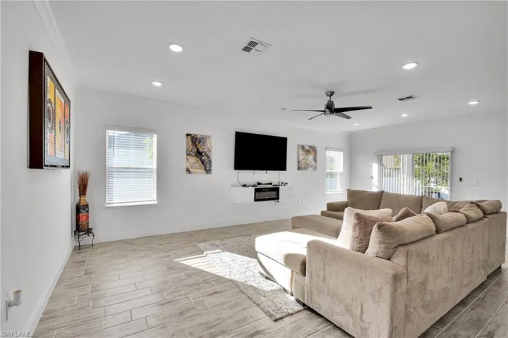 Living area with crown molding, wood tiled floors, a ceiling fan, and recessed lighting