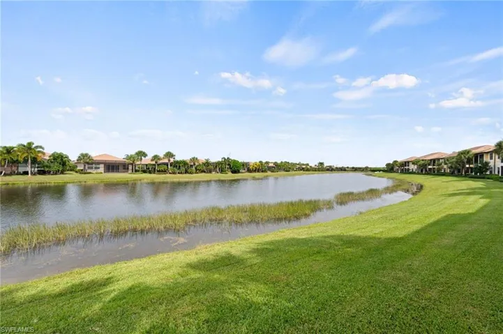 Expansive grassy area bordering a body of water with lush vegetation