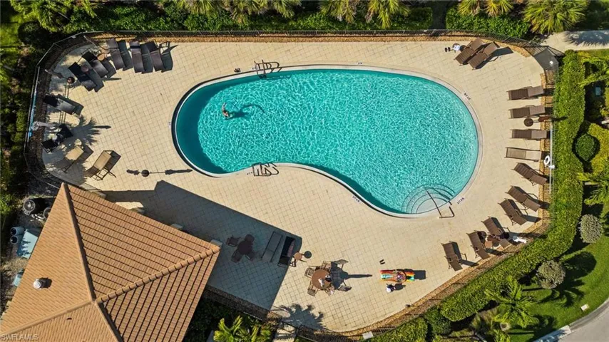 Curved swimming pool with integrated steps, surrounded by a light-toned paver deck