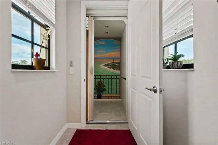 Panel door with satin nickel hardware, tile flooring, and windows with horizontal blinds