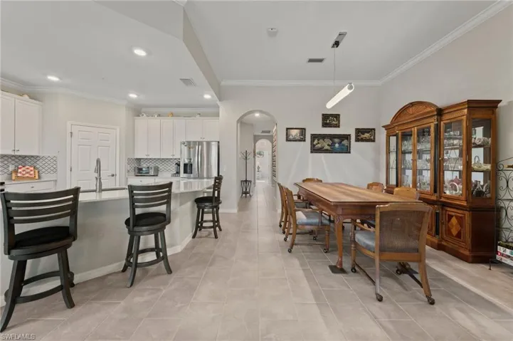Kitchen featuring white cabinetry, stainless steel appliances, a tile backsplash, and a breakfast bar