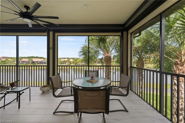 Screened lanai featuring light-toned tile flooring, black ceiling fan, and black railing