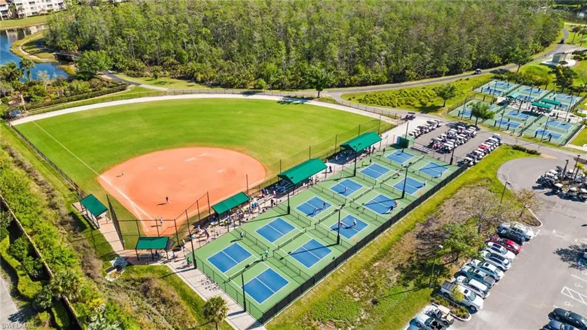 Expansive outdoor recreation area featuring a baseball diamond, multiple pickleball courts, and paved parking facilities