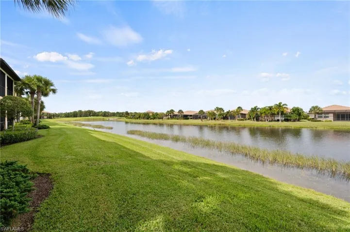 Expansive green lawn with mature palm trees and lush landscaping bordering a tranquil waterway