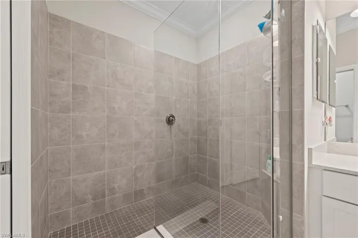 Glass-enclosed shower with full-height gray tile, mosaic floor tile, and a built-in shower niche