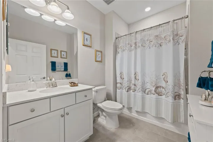 Bathroom featuring a white vanity with an integrated sink, polished chrome faucet, and a large mirror with overhead lighting