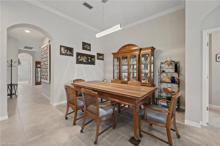 Recessed lighting, crown molding, arched entryway, tile flooring, and a linear pendant light fixture