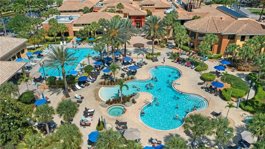 Multiple resort-style pools, a spa, surrounding low-rise buildings with terracotta-style roofing, and mature palm landscaping