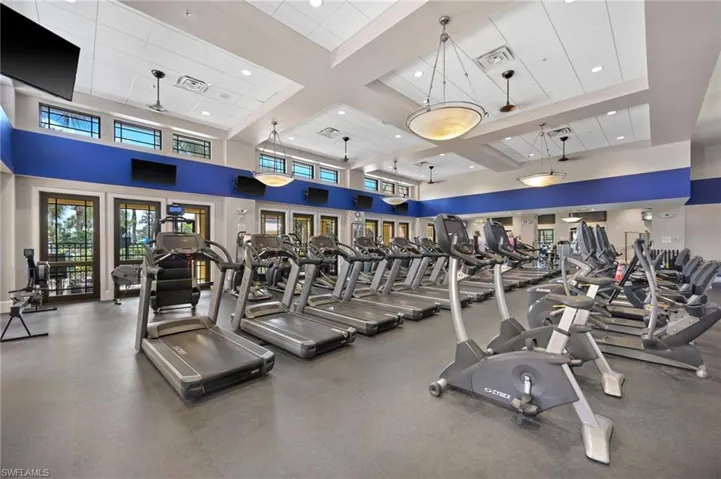 Fitness center featuring multiple cardio machines, high ceilings, recessed lighting, and transom windows