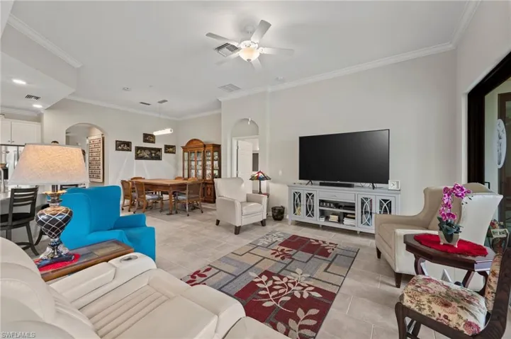 Open concept living area with crown molding, tiled flooring, and arched doorways