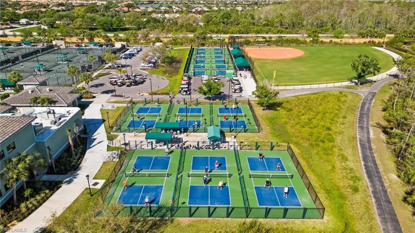 Multiple pickleball courts, several tennis courts, a baseball field, extensive paved pathways, and a building with a tile roof