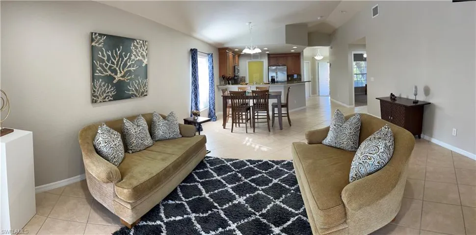 Living room featuring a chandelier, vaulted ceiling, light tile patterned floors, and plenty of natural light