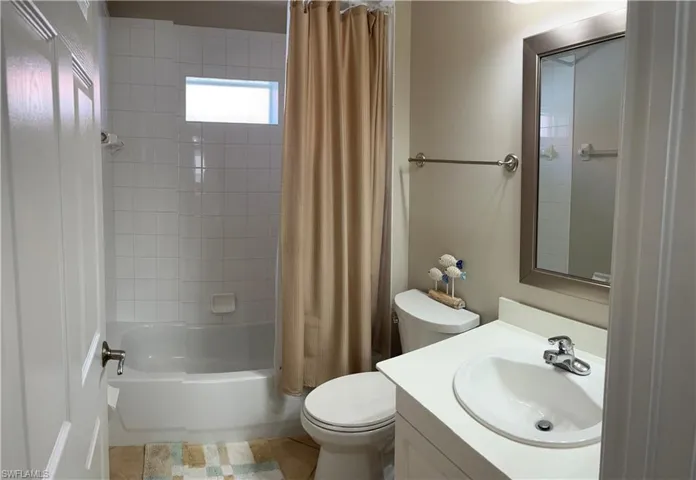 Full bathroom featuring toilet, shower / bath combo with shower curtain, vanity, and tile patterned flooring