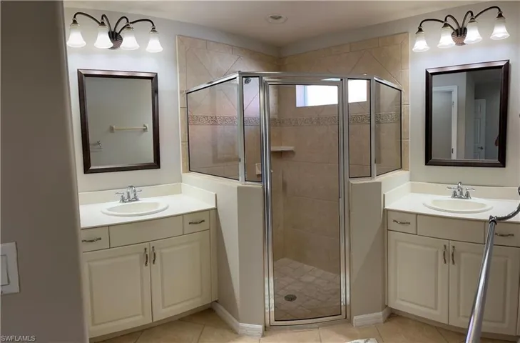 Bathroom featuring vanity, a shower with shower door, and tile patterned flooring