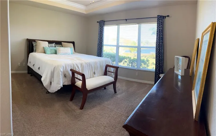 Carpeted bedroom featuring ornamental molding and a tray ceiling