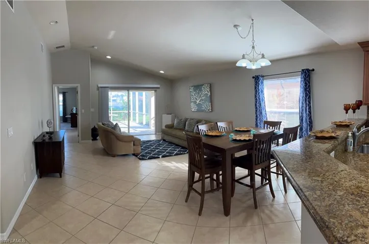 Dining room with a chandelier, light tile patterned floors, plenty of natural light, and vaulted ceiling