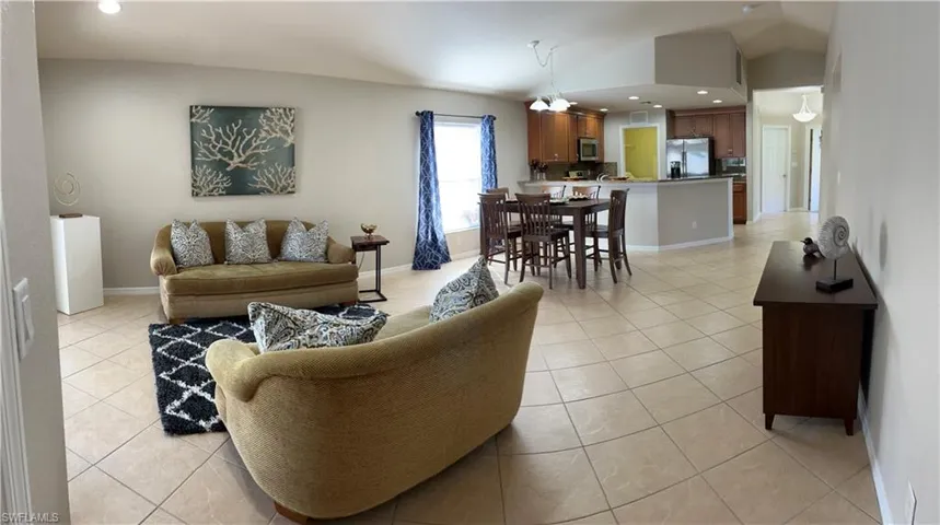 Living room with vaulted ceiling, a notable chandelier, and light tile patterned flooring