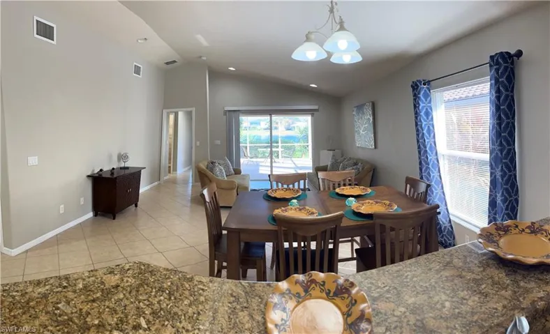 Dining space featuring lofted ceiling, a chandelier, and light tile patterned floors
