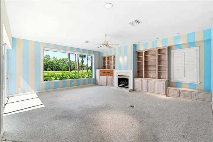 Unfurnished living room featuring built in features, ceiling fan, and carpet flooring