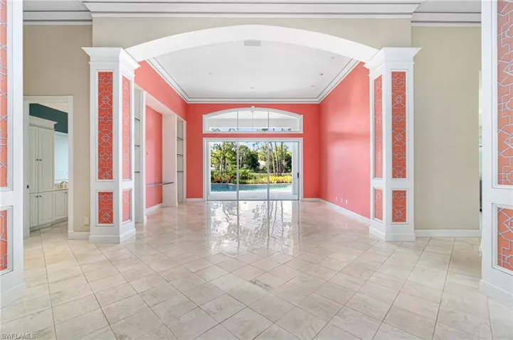 Spare room with ornamental molding, decorative columns, and light tile floors
