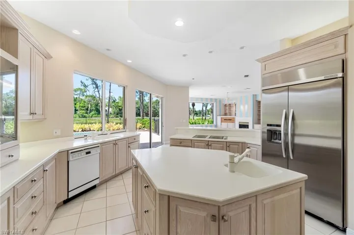 Kitchen featuring kitchen peninsula, dishwasher, light brown cabinetry, sink, and built in refrigerator