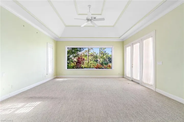 Primary suite with a tray ceiling, carpet flooring, plenty of natural light, and ceiling fan