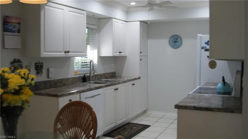 Kitchen with white cabinets, white appliances, ceiling fan, light tile patterned flooring, and crown moldingGranite countertops