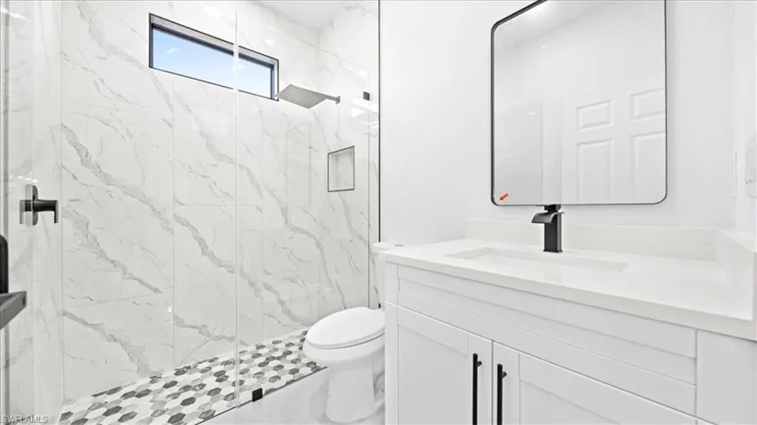 Bathroom featuring vanity and a marble finish shower