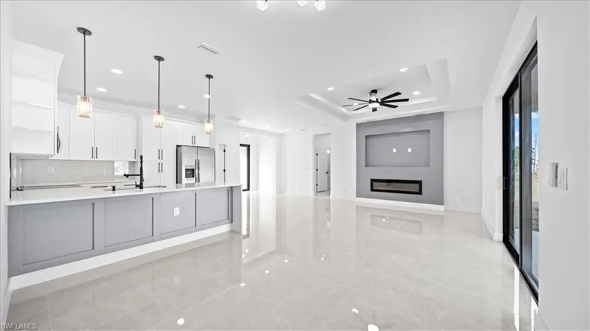 Kitchen featuring white cabinetry, decorative light fixtures, stainless steel refrigerator with ice dispenser, open shelves, and open floor plan