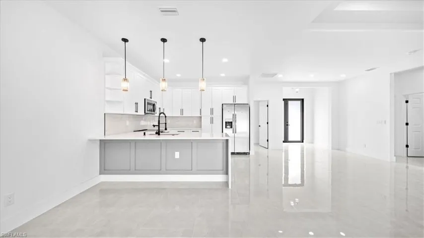 Kitchen featuring open shelves, stainless steel appliances, decorative light fixtures, white cabinets, and a peninsula