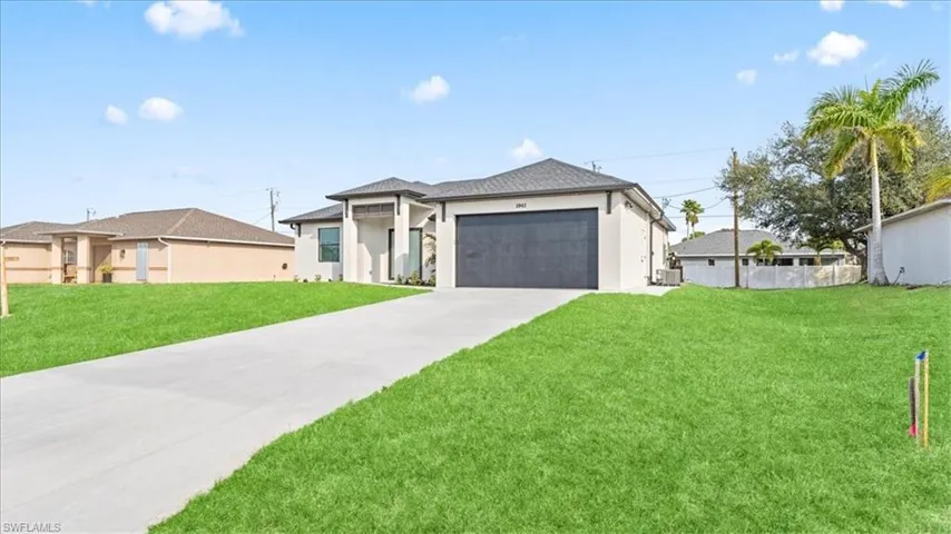 Prairie-style house with a front lawn, an attached garage, driveway, and stucco siding