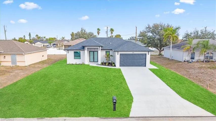 View of front facade with a residential view, concrete driveway, a front lawn, a garage, and stucco siding