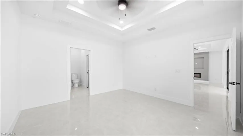 Unfurnished room with ceiling fan and a raised ceiling