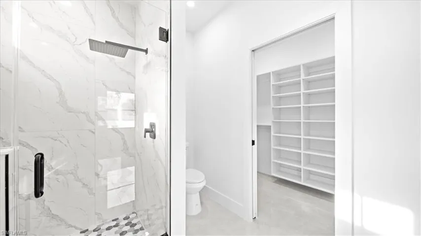 Full bath featuring a spacious closet and a marble finish shower