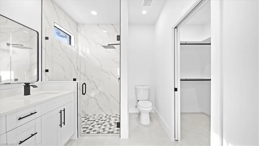 Full bathroom featuring a walk in closet, vanity, a marble finish shower, and recessed lighting