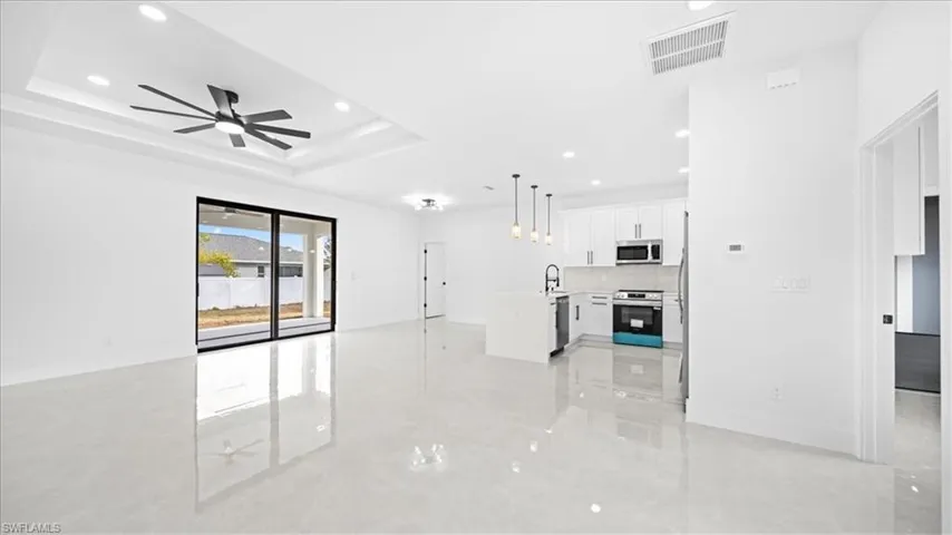 Unfurnished living room with recessed lighting, ceiling fan, and a tray ceiling