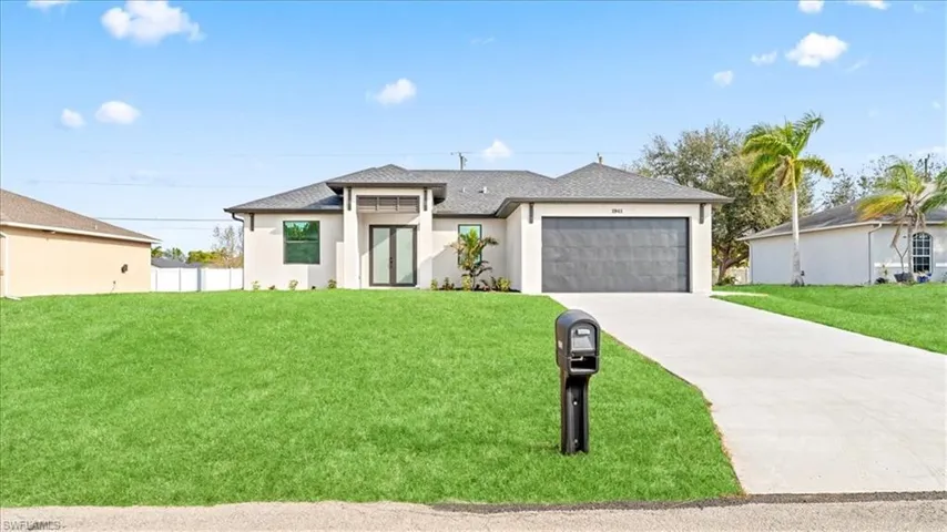 View of front of house with a front lawn, driveway, an attached garage, and stucco siding