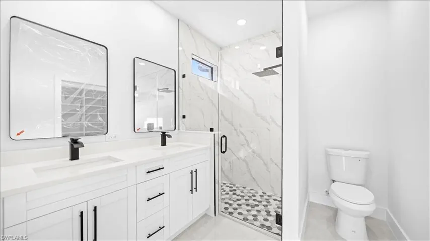 Full bathroom with double vanity, a marble finish shower, and recessed lighting
